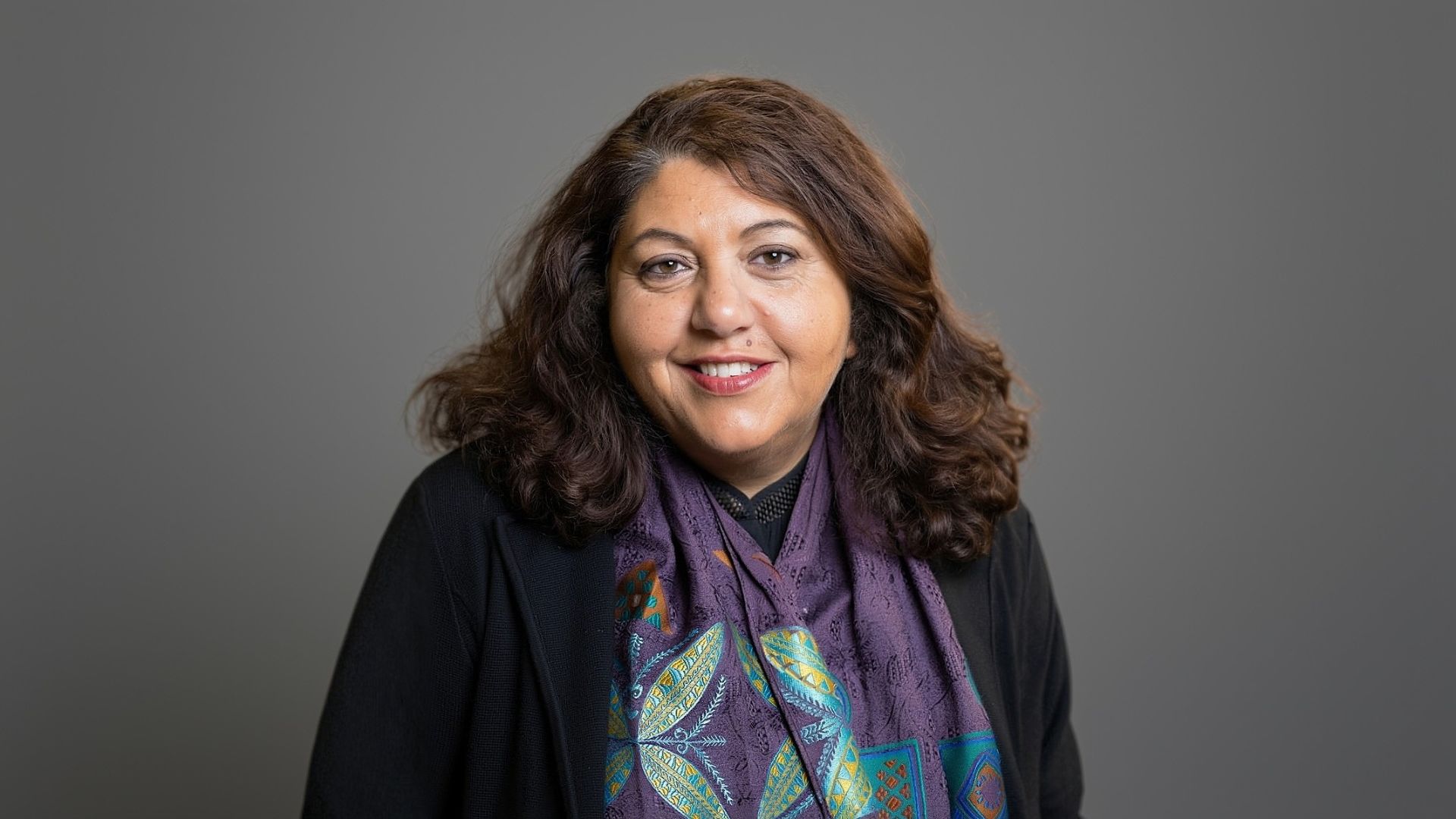 Rima Kaddurah-Daouk, PhD, in front of plain black and grey background